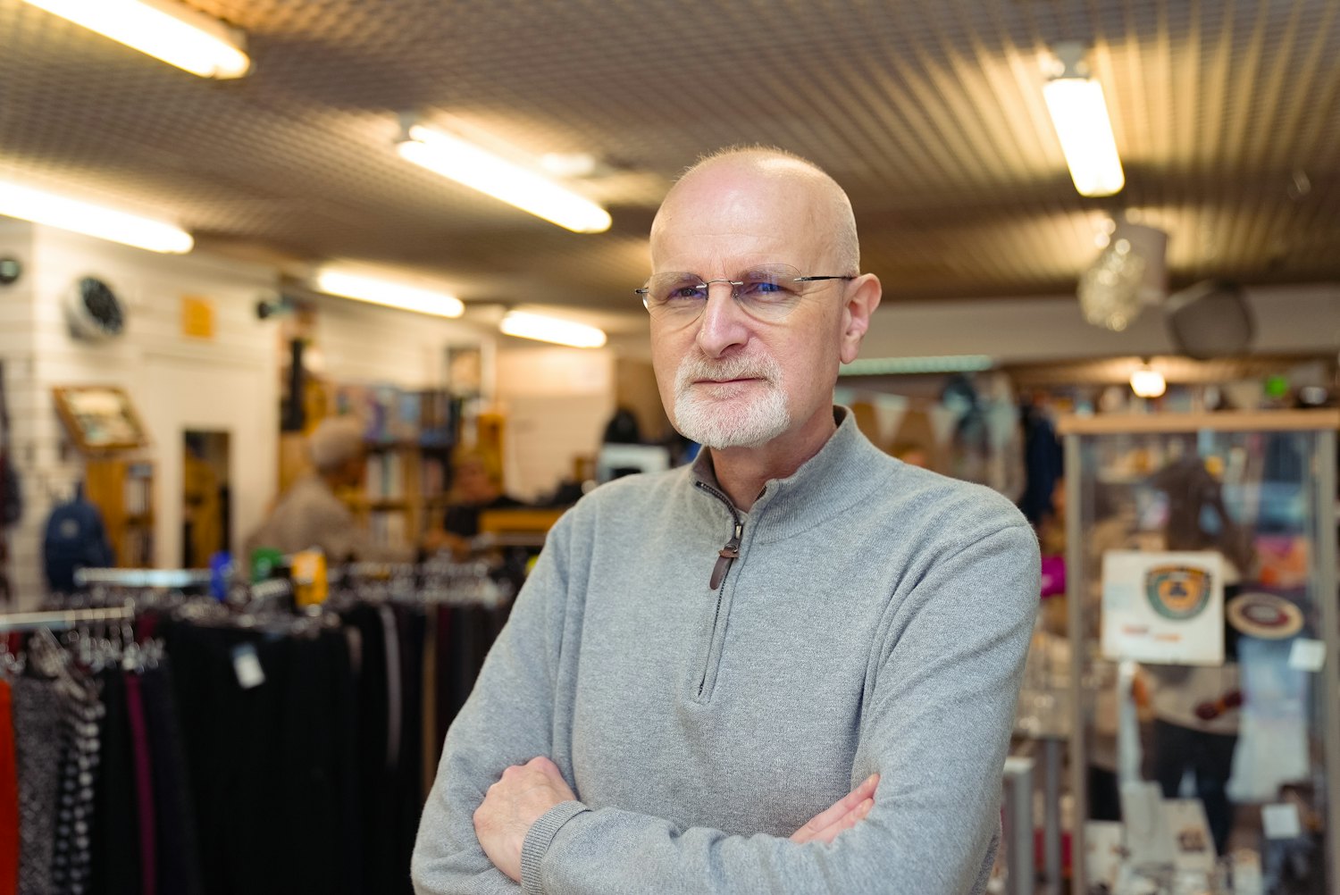 The owner of an independent shop standing behind the counter of his store